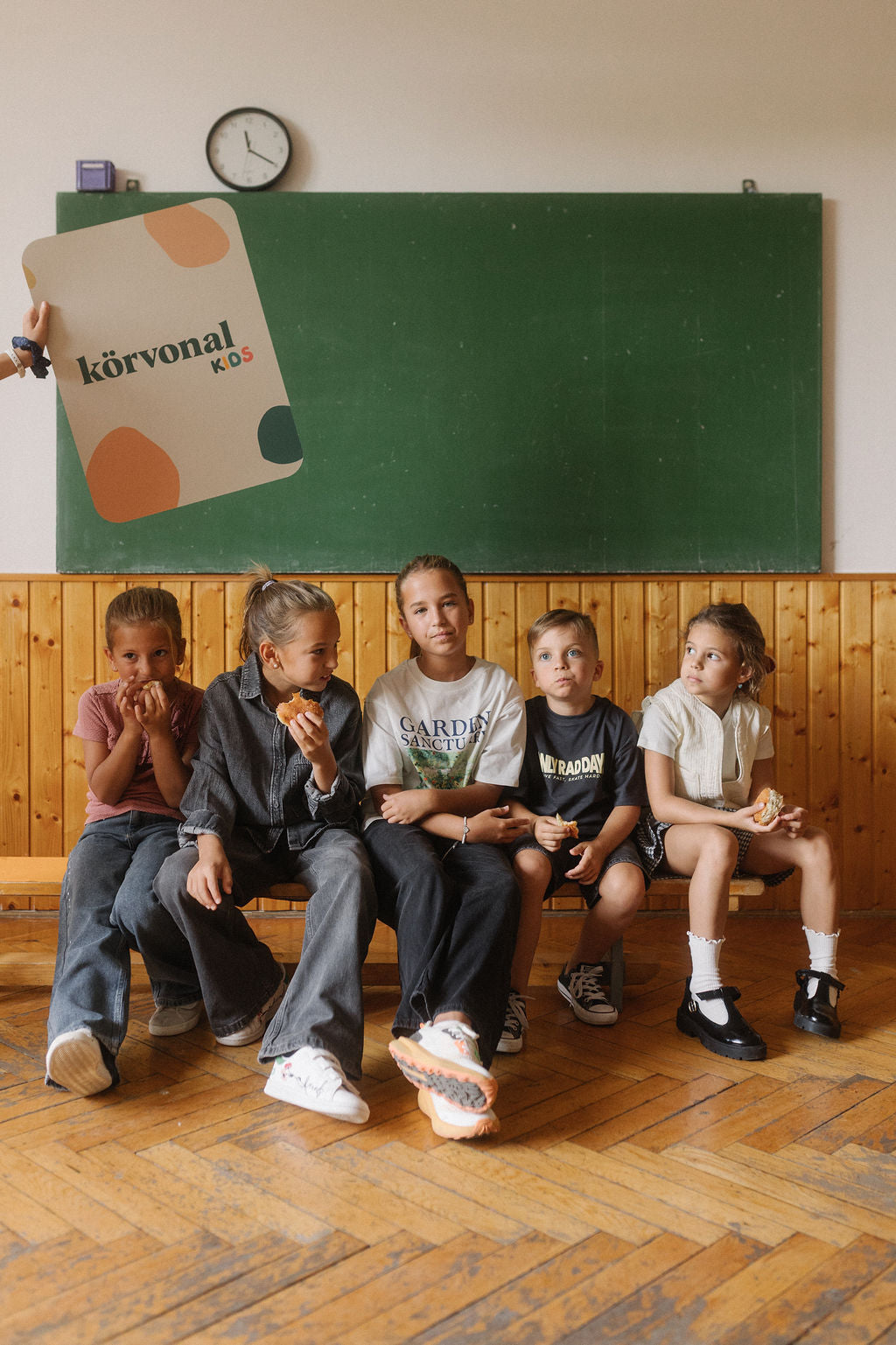 Gyerekek egy padon ülnek a tábla előtt, körvonal kids kártyákkal